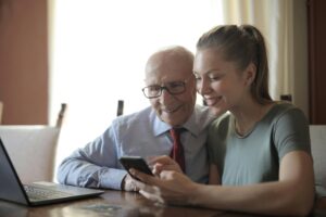 Young woman helping older gentleman with technology